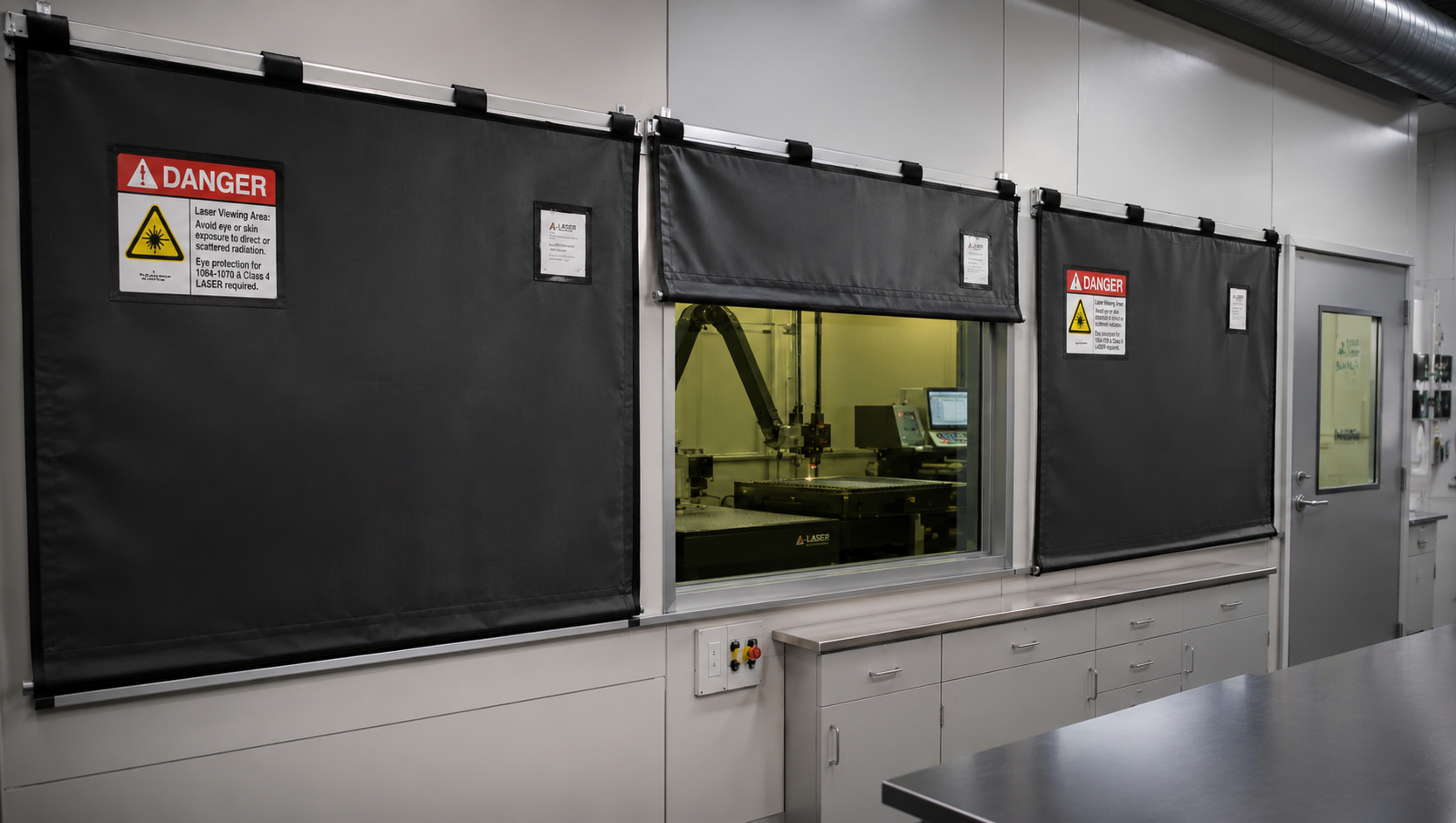 Laser safety window coverings installed over observation windows in an industrial laser processing room